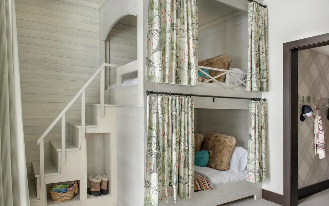 A room with bunk beds and stairs leading to the top floor.