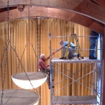 Two men working on a ceiling in a room.